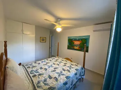 a bedroom with a bed and a painting on the wall at 2 BR & 1WR Suite at Villa Costa Verde near Playa Cofresi, Puerto Plata with a pool, balcony, and a rooftop terrace in San Felipe de Puerto Plata