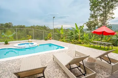 a swimming pool with chairs and a red umbrella at The American Dream in Jarabacoa