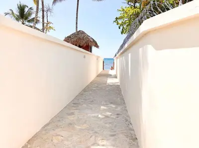a white fence on the beach with the ocean in the background at Beautiful and peaceful 2-bedroom family condo in Juan Dolio