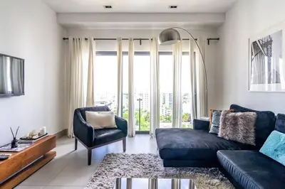 a living room with a blue couch and a large window at Dream Rooftop Downtown View in Santo Domingo