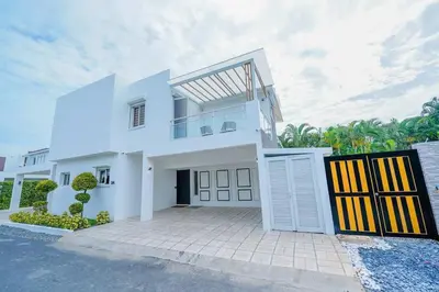 a white house with a gate in front of it at Villa Hermosa en Metro Country Club Juan Dolio in Juan Dolio