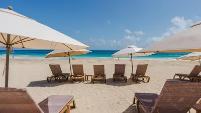 a group of chairs and umbrellas on a beach at 1BDR Rockstar's Paradise in front of Hard Rock H. in Punta Cana