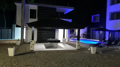 a patio with a grill and a swimming pool at night at LEVEL suites premium in Sosúa