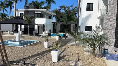 a house with a courtyard with palm trees and a swimming pool at LEVEL suites premium in Sosúa