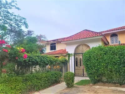 a house with a gate and some bushes and flowers at Linkzup Playa Laguna Villa in Sosúa