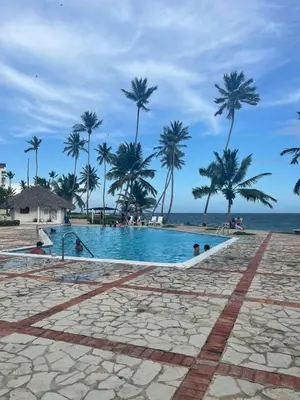 a swimming pool on the beach with palm trees at Estancia Nana Tu Refugio con Vista al Mar, Piscina, wifi, lavadora secadora Reserva Ahora in Juan Dolio