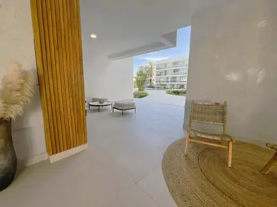 a living room with a chair and a mirror at Exclusivo penthouse con piscina en Playa Bávaro in Punta Cana
