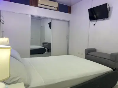 a bedroom with a bed and a couch and a mirror at Bello y acogedor Apartamento in Santiago de los Caballeros