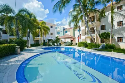 a swimming pool in a resort with palm trees at Cozy 2 bed apartment garden views close to Playa Bavaro in Punta Cana