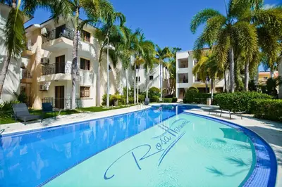 a swimming pool in front of a building with palm trees at Cozy 2 bed apartment garden views close to Playa Bavaro in Punta Cana