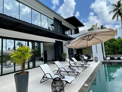 a house with a pool and chairs and an umbrella at Casa black and white frente al mar in Las Galeras
