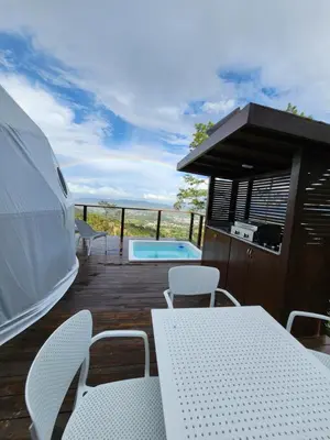 a deck with a table and chairs and a swimming pool at The Domes Jarabacoa in Jarabacoa