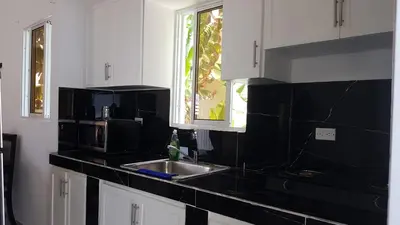 a kitchen with white cabinets and a sink and a window at Villa el real los patos in Los Patos