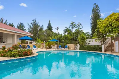 a swimming pool at a resort with chairs and umbrellas at El Neptuno Residencial, Sosua in Sosúa