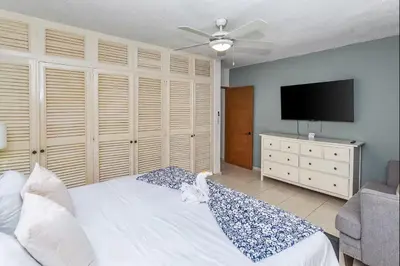 a bedroom with a white bed and a flat screen tv at El Neptuno Residencial, Sosua in Sosúa
