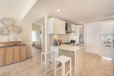 a kitchen with white cabinets and white stools in it at Exceptional apartment nearby beach at Portillo in Las Terrenas