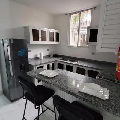 a kitchen with a counter with chairs and a refrigerator at Departamento Estrella en Santo Domingo in Santo Domingo