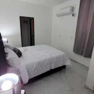 a white bedroom with a bed and a sink at Departamento Estrella en Santo Domingo in Santo Domingo