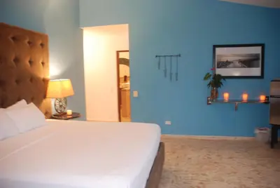a bedroom with a white bed and a blue wall at E&J Boutique Residences in Sosúa