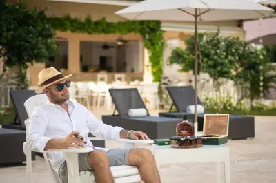 a man in a hat sitting at a table at Los Flamencos Aparthotel Beach Club in Bayahibe