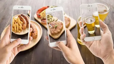 two people taking pictures of food and drinks on a table at Estilo & Confort in Mendoza