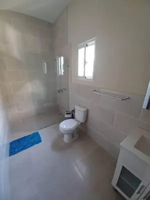 a white bathroom with a toilet and a window at Villa Xiomara in El Jamo