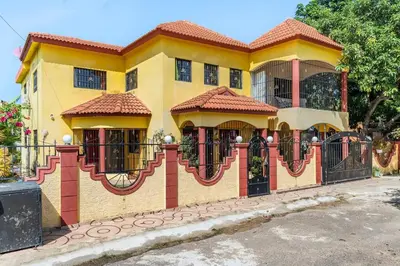 a yellow house with a fence in front of it at Casa para vacacionar - El patio de Olivia in San Felipe de Puerto Plata