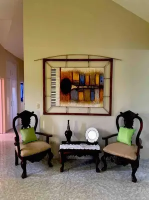two chairs and a table in a room with a painting at Casa para vacacionar - El patio de Olivia in San Felipe de Puerto Plata