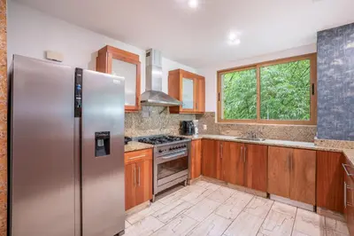 a kitchen with a stainless steel refrigerator and wooden cabinets at Magical apartment with garden view in Casa de Campo in El Infiernito
