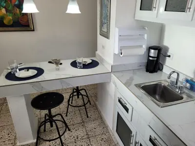 a small kitchen with white counters and a sink at Cozy Apartment Studio in Santo Domingo