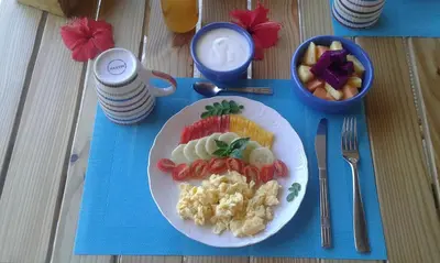 a plate of food with eggs and fruit on a table at B&B El Mirador al Mar in Sosúa