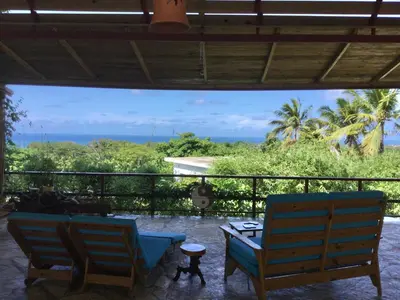a patio with two chairs and a table and the ocean at B&B El Mirador al Mar in Sosúa