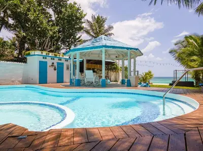 a swimming pool with a gazebo next to the ocean at Dolce Casa in Juan Dolio