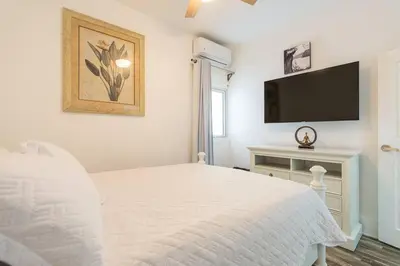 a white bedroom with a bed and a flat screen tv at Dolce Casa in Juan Dolio