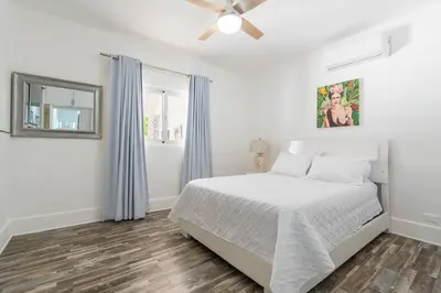 a white bedroom with a bed and a ceiling fan at Dolce Casa in Juan Dolio