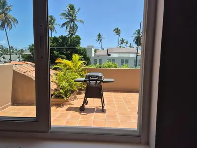 a grill seen through a window with a view of a patio at bello PH cerca de la playa in Punta Cana