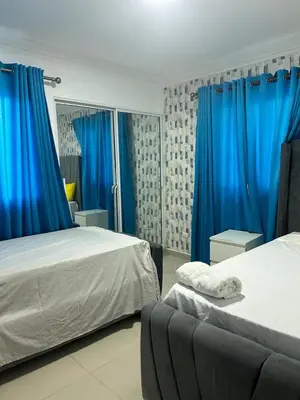 a bedroom with two beds and blue curtains at Apartamento con Deslumbrante Vista Al Mar in La Francia