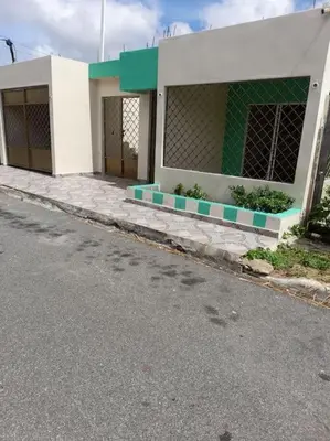 a white and green building on the side of a street at Maison T4, près de la mer in La Romana