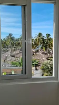 a window with a view of a beach and palm trees at apartamento luxury in La Laguna