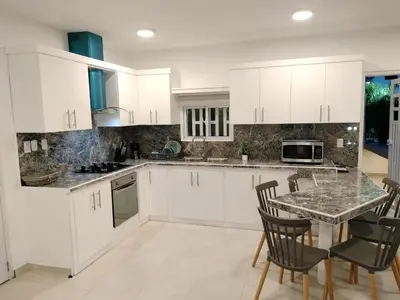 a kitchen with white cabinets and a table and chairs at Agréable appartement en rooftop in La Cabirma