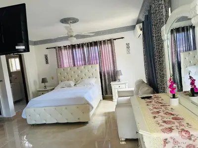 a bedroom with a large white bed and a couch at Casa completa con hermosa vista in San Felipe de Puerto Plata