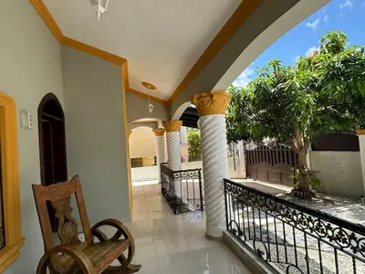 a room with a balcony with columns and a chair at Casa completa con hermosa vista in San Felipe de Puerto Plata