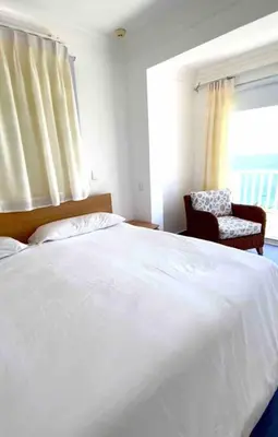 a bedroom with a white bed with a chair and a window at Ocean Front Deluxe Condo in Punta Balandra