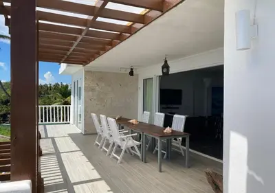 a patio with a wooden table and white chairs at Ocean Front Deluxe Condo in Punta Balandra