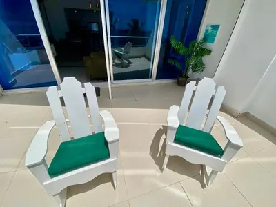 two white chairs with green cushions sitting in a room at LasOlasTower JuanDolio-2Br-3Bds-7Px-WiFi-SeaView in Juan Dolio