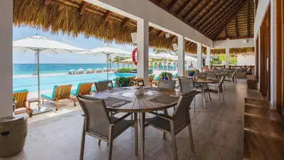 a restaurant with tables and chairs and the ocean at Paradise 1BDR APT in front of Hard Rock Hotel in Punta Cana