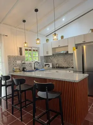 a kitchen with a counter with chairs and a refrigerator at Luz de Luna Emotions in Santo Domingo