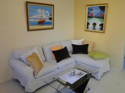 a living room with a white couch and paintings at Apartamento Carmil I in Santo Domingo