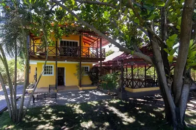 a yellow house with a balcony and trees at Casa Palmar - Finca in Palmar Arriba