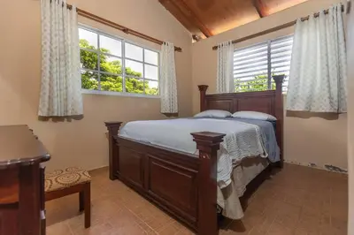 a bedroom with a wooden bed and two windows at Casa Palmar - Finca in Palmar Arriba